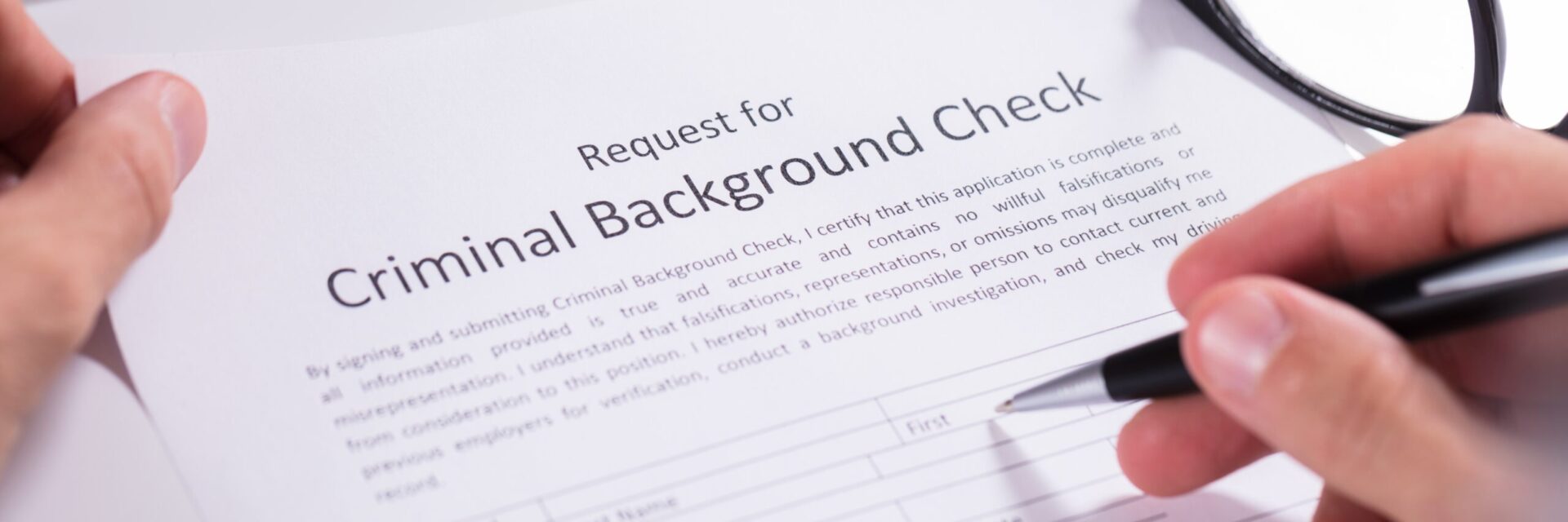Criminal background check request form being filled in with a pen
